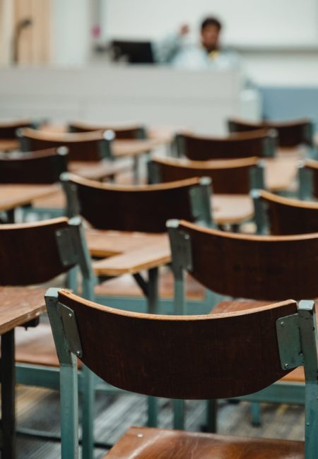 Wooden lecture chairs arranged in the classroom. Empty college classroom with many wooden lecture chairs but no students. Back to school concept.
